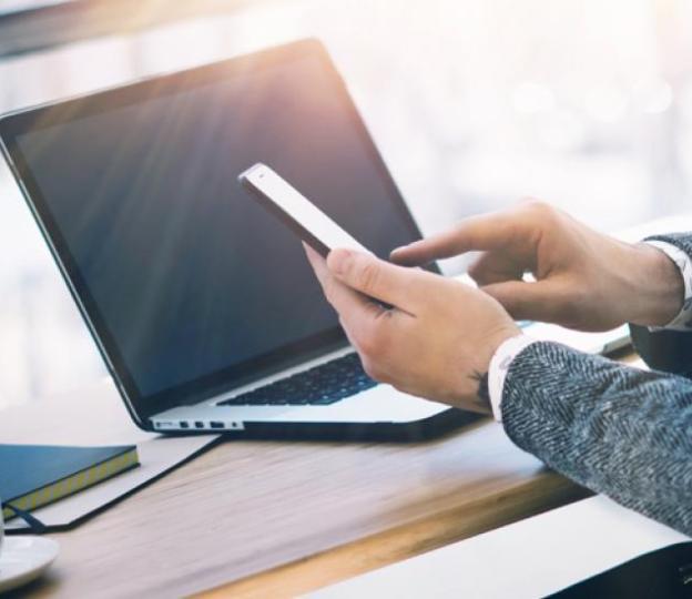 Closeup of person using phone and laptop